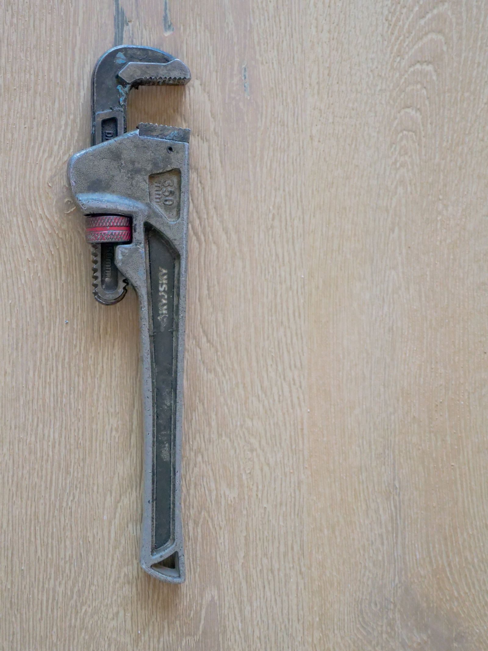 A pipe wrench resting on a wooden worktop