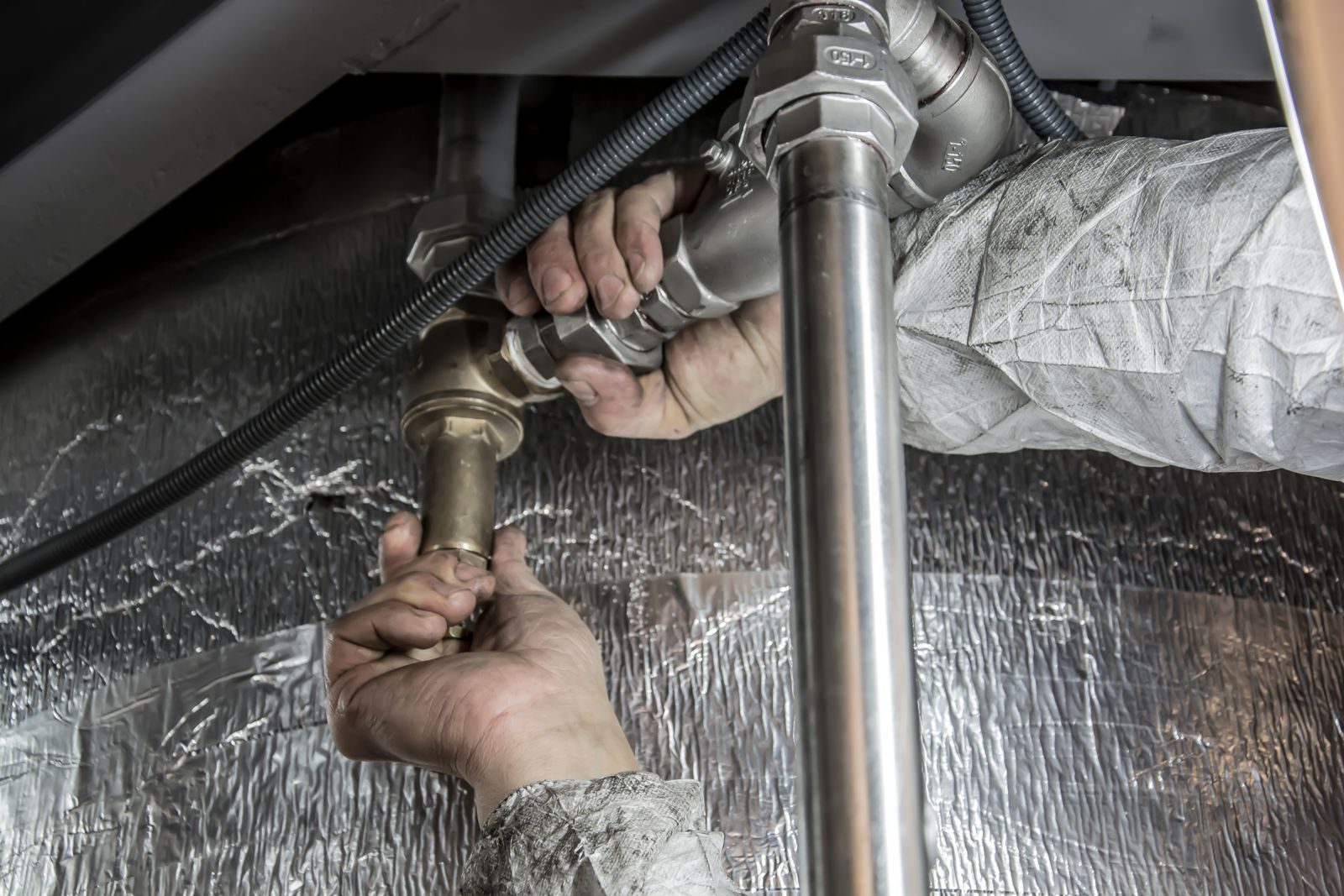 Hands tightening a brass compression fitting on copper pipework